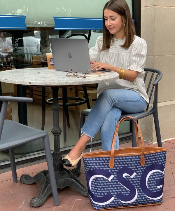 A blue monogrammed tote bag with leather trim